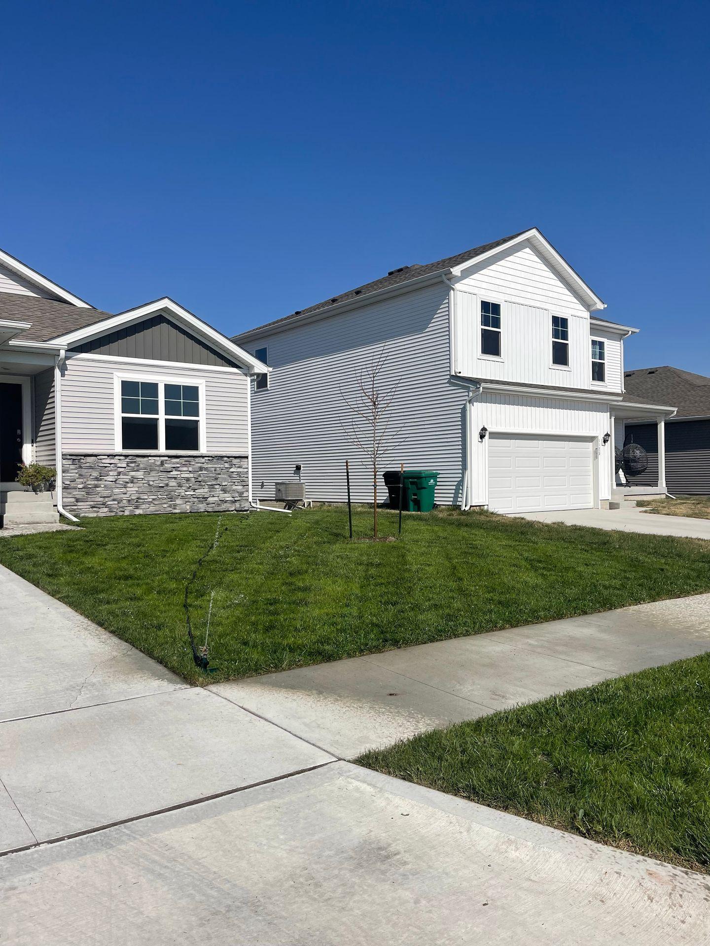 Suburban street view with modern two-story houses and green lawns on a sunny day.