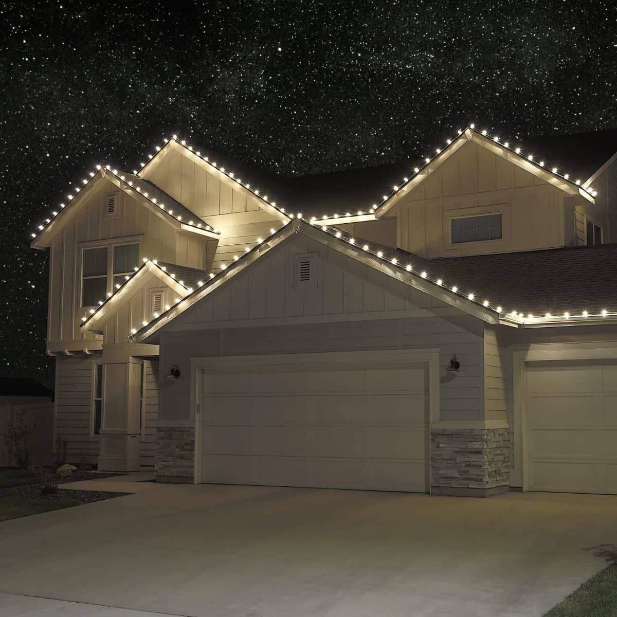 House with roofline decorated with string lights under a starry night sky.