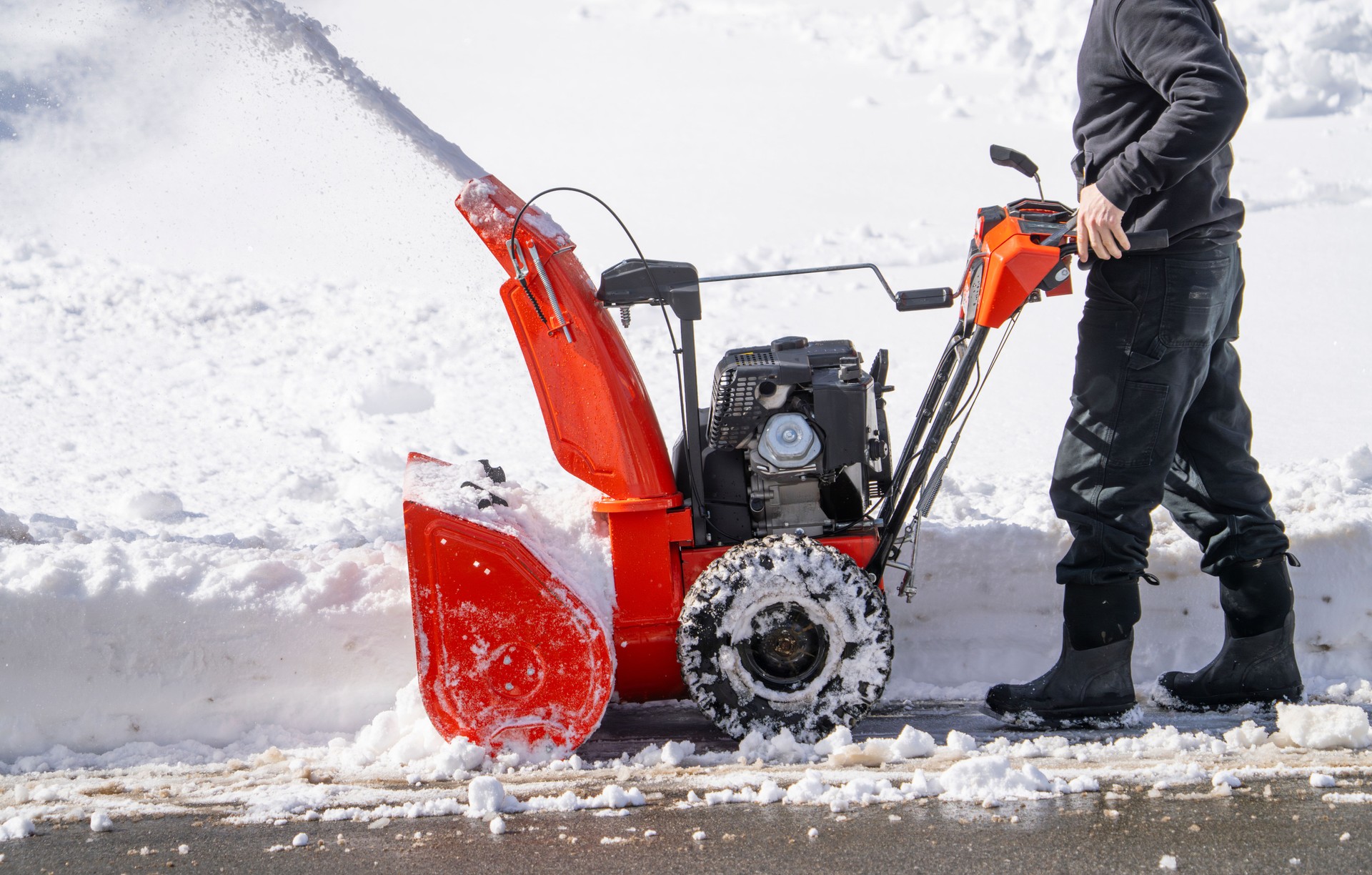 man removing snow on the driveway of the house by snow blower