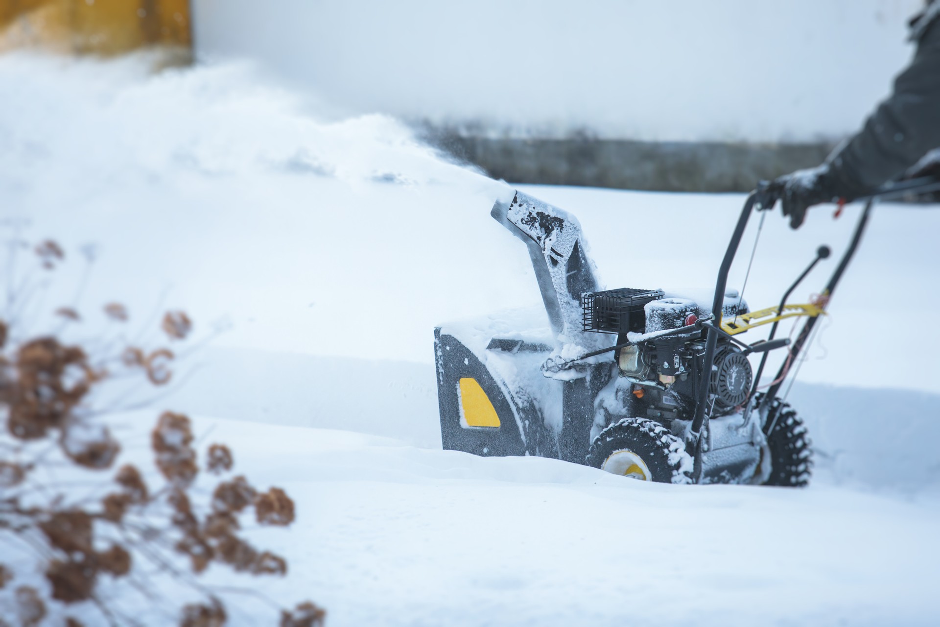 Process of removing snow with portable blower machine, worker dressed in overall workwear with gas snow blower removal on the street during winter